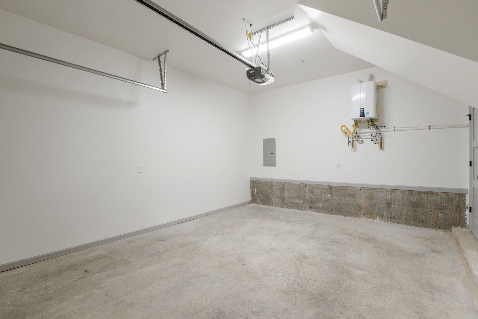 An empty garage with a garage door opener hanging from the ceiling.