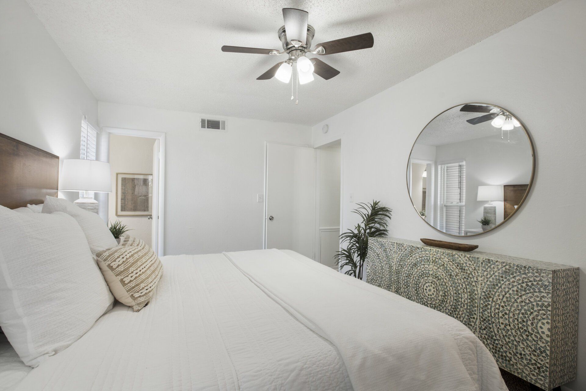 A bedroom with a bed , dresser , mirror and ceiling fan.