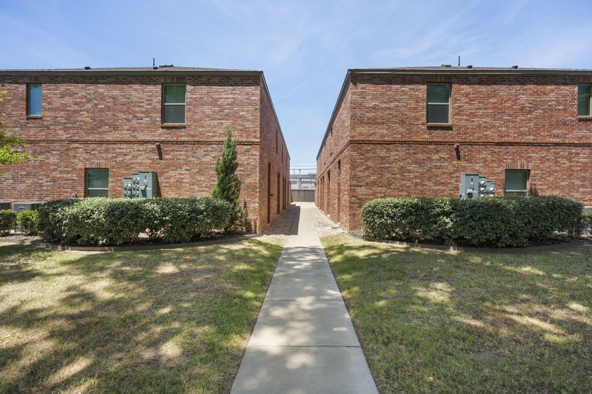Two brick buildings with a sidewalk between them