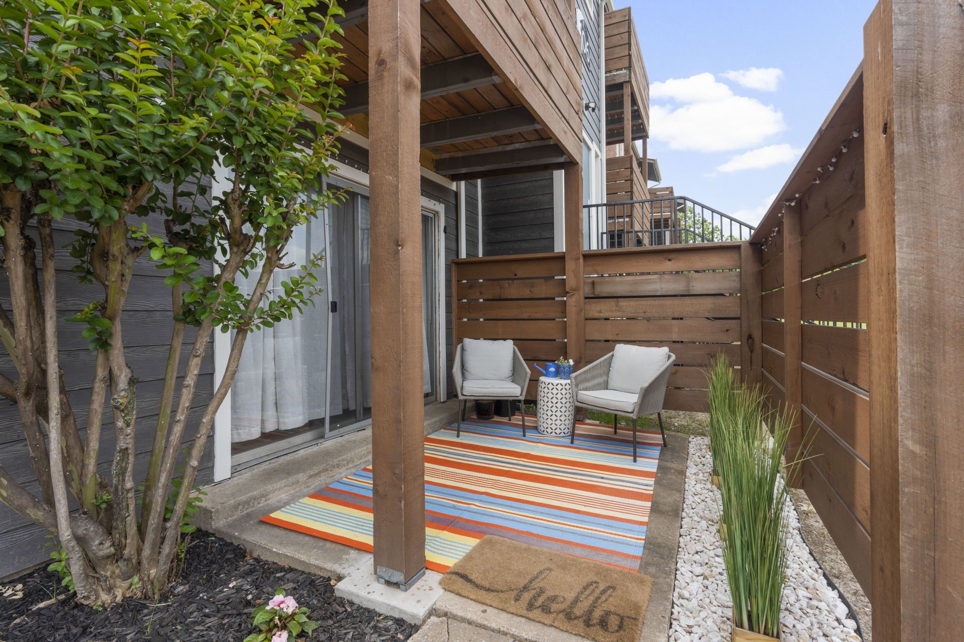 There is a patio with chairs and a welcome mat.
