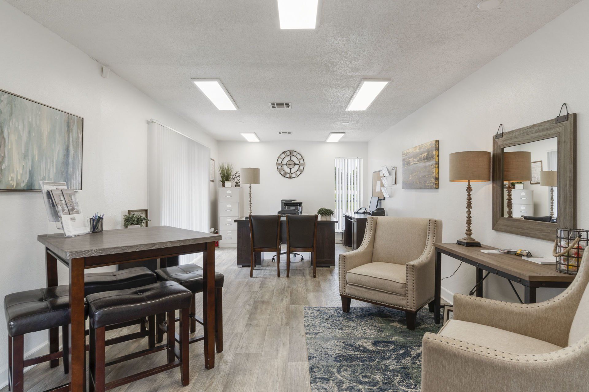 A living room with a table and chairs and a clock on the wall.