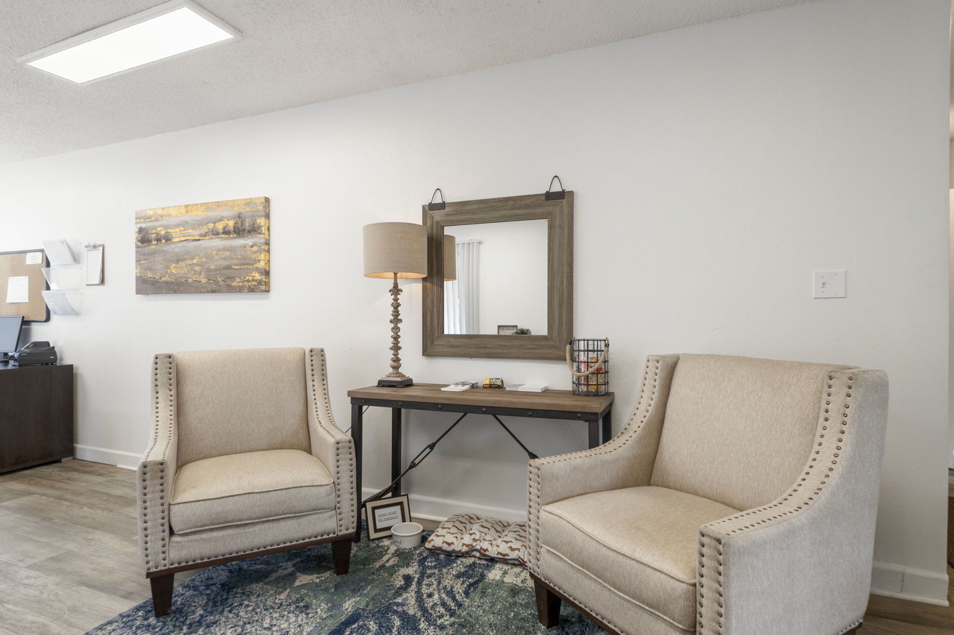 A living room with two chairs , a table and a mirror.