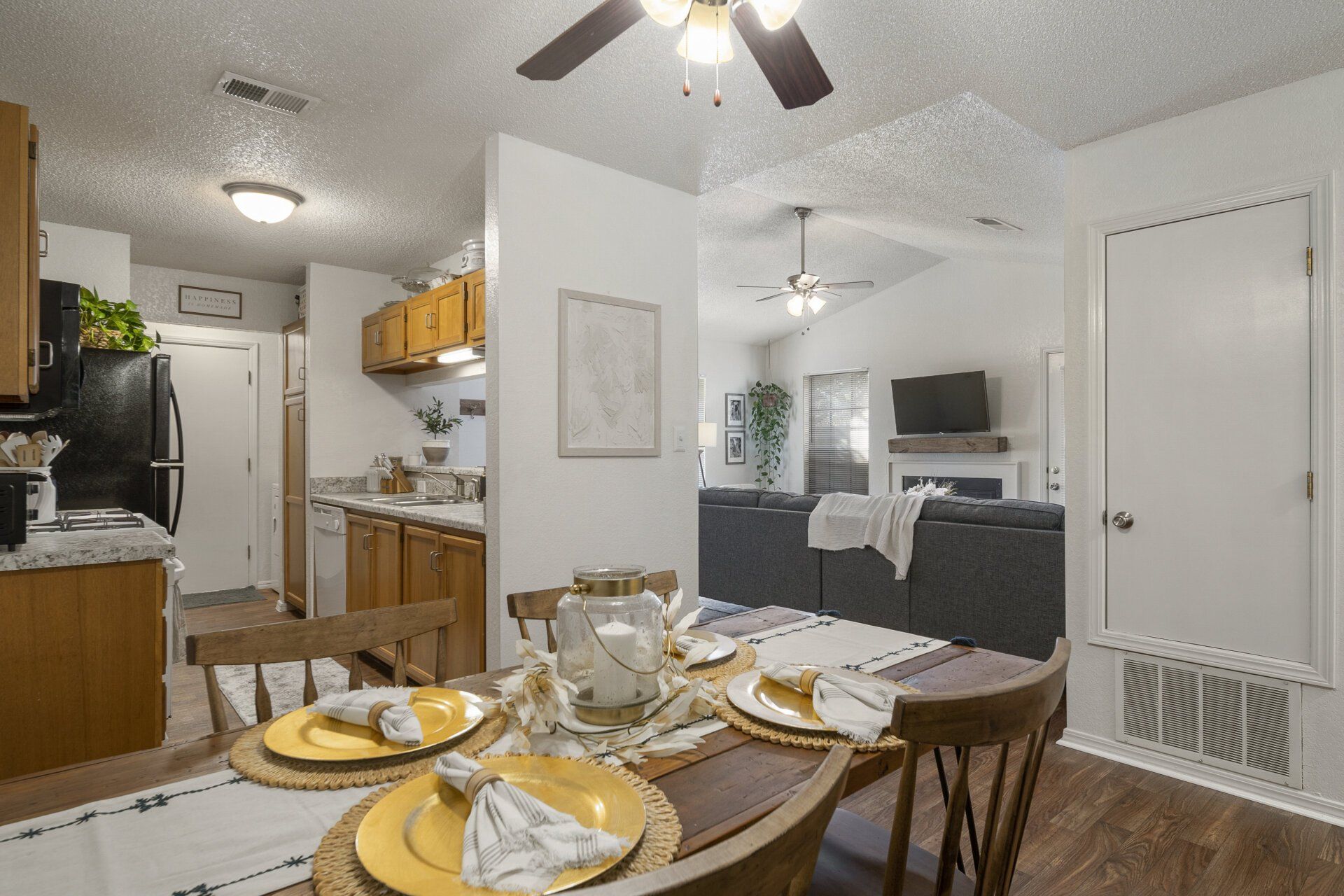 A dining room table with plates and napkins on it in a house with a ceiling fan.