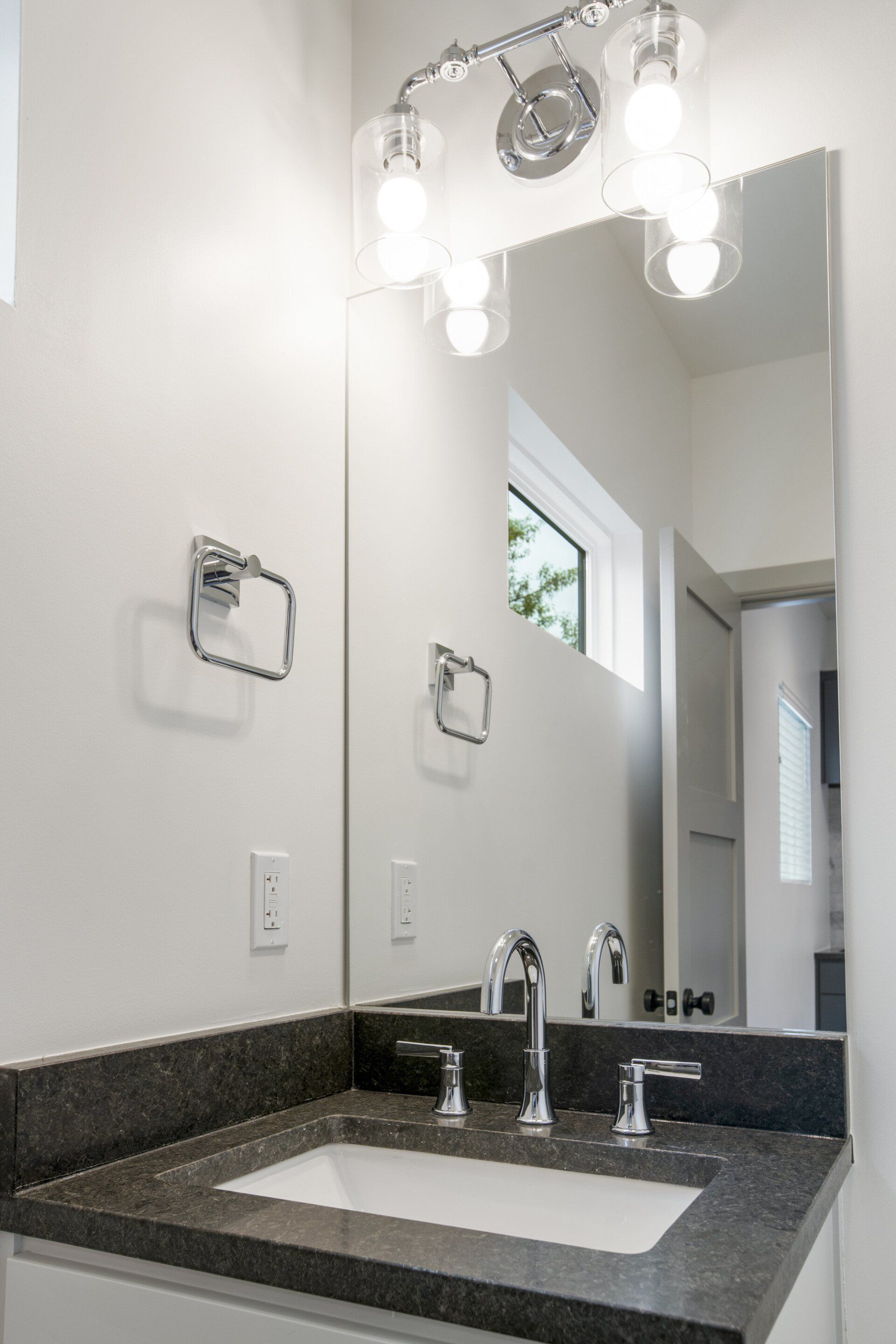 A bathroom with a sink , mirror and light fixture.