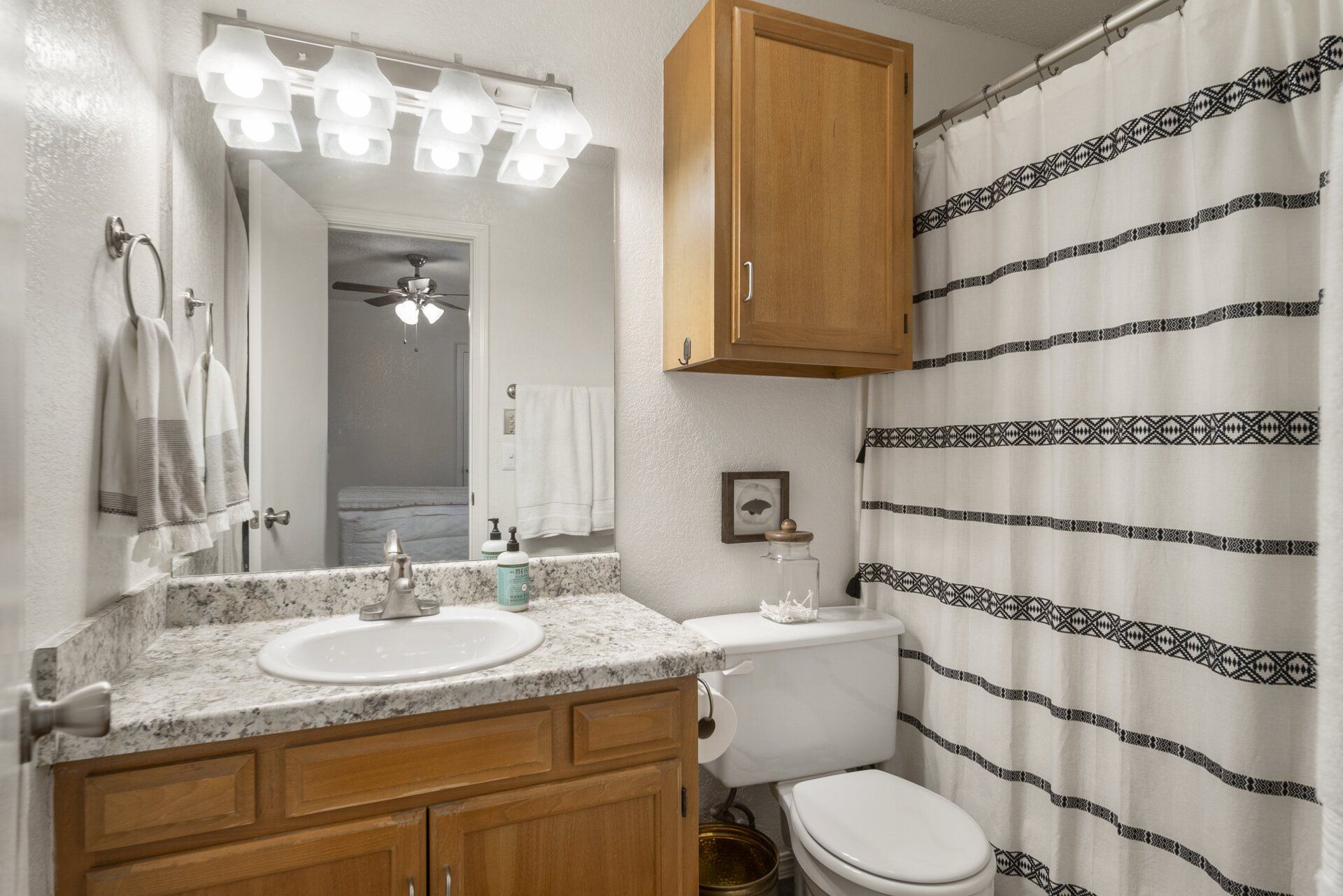 A bathroom with a sink , toilet , shower curtain and mirror.