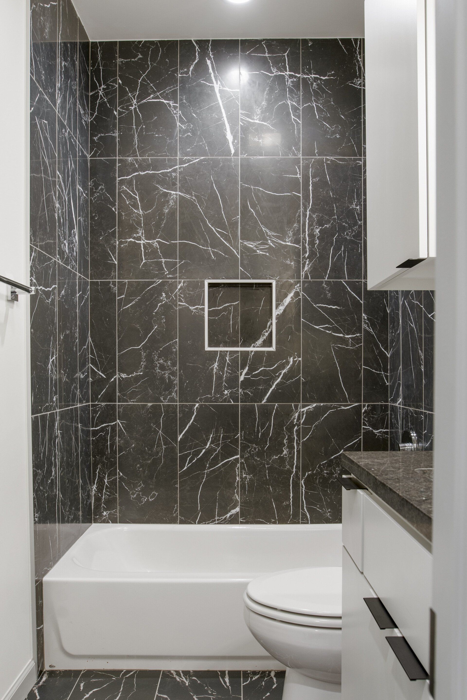 A bathroom with a tub , toilet , sink and shower.