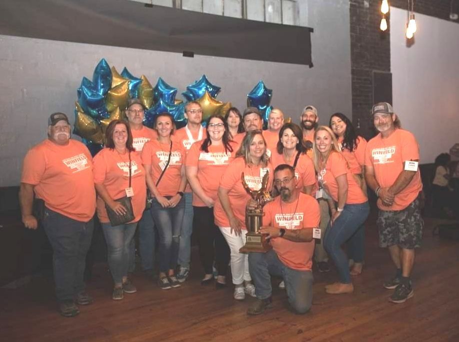 A group of people wearing orange shirts are posing for a picture.