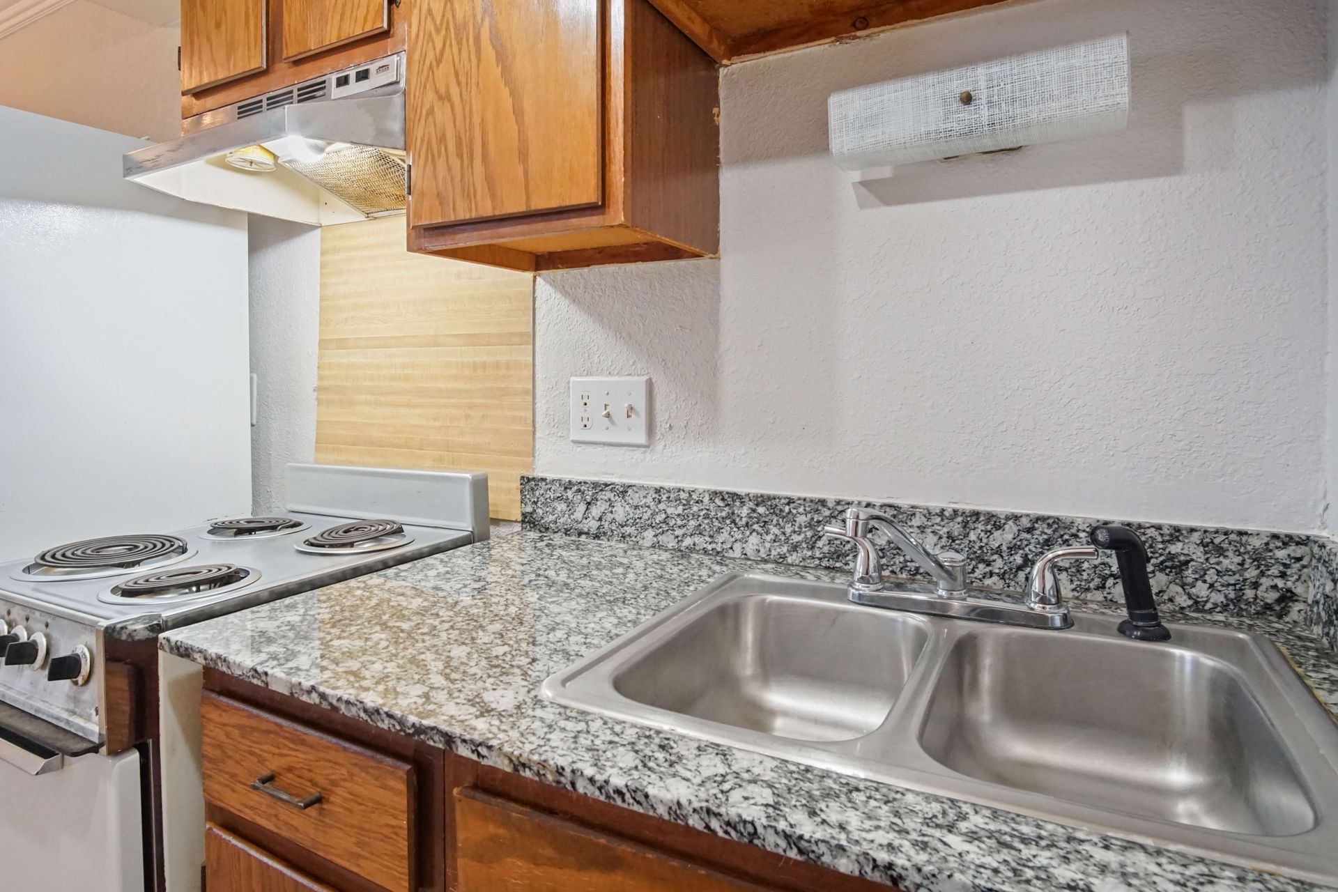 A kitchen with a sink , stove , and cabinets.