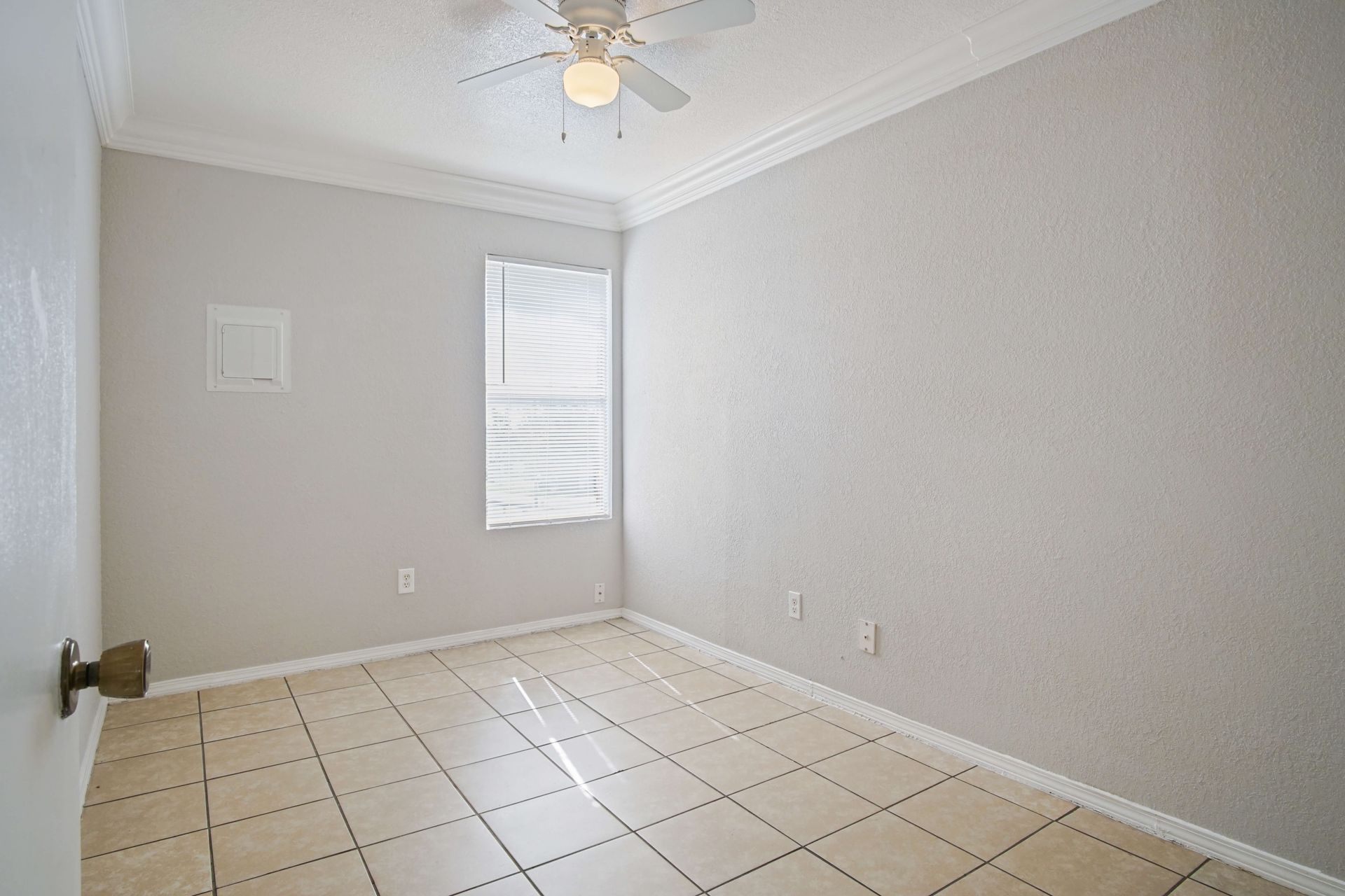 An empty bedroom with a ceiling fan and a window.