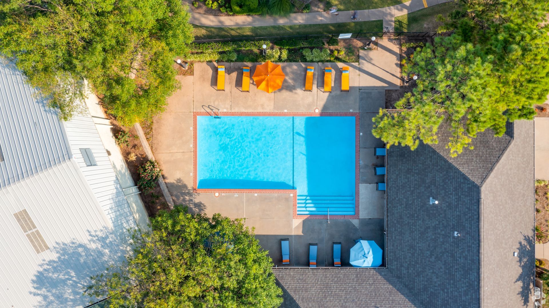 An aerial view of a swimming pool surrounded by trees and chairs.