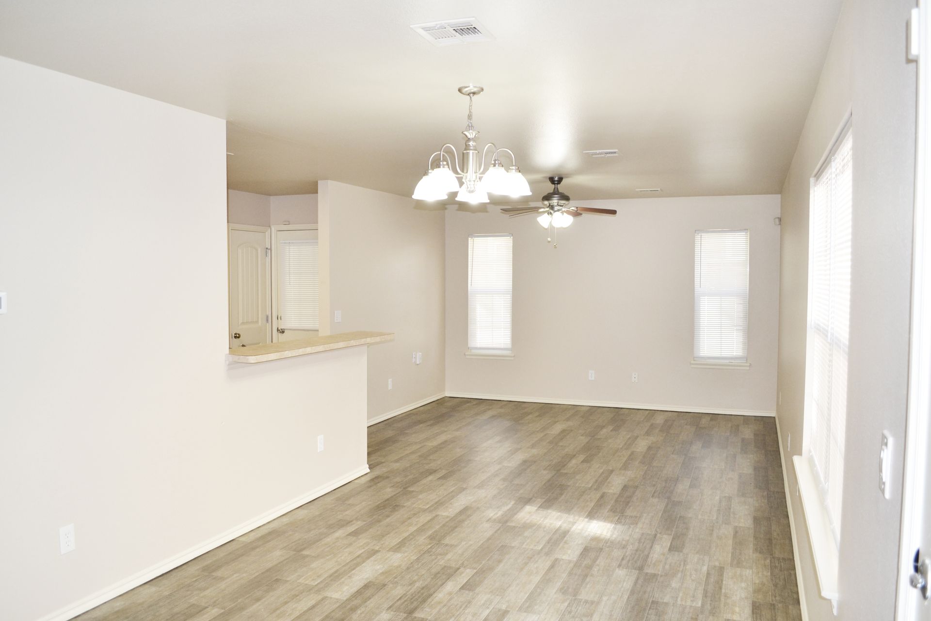 An empty living room with hardwood floors and a ceiling fan.