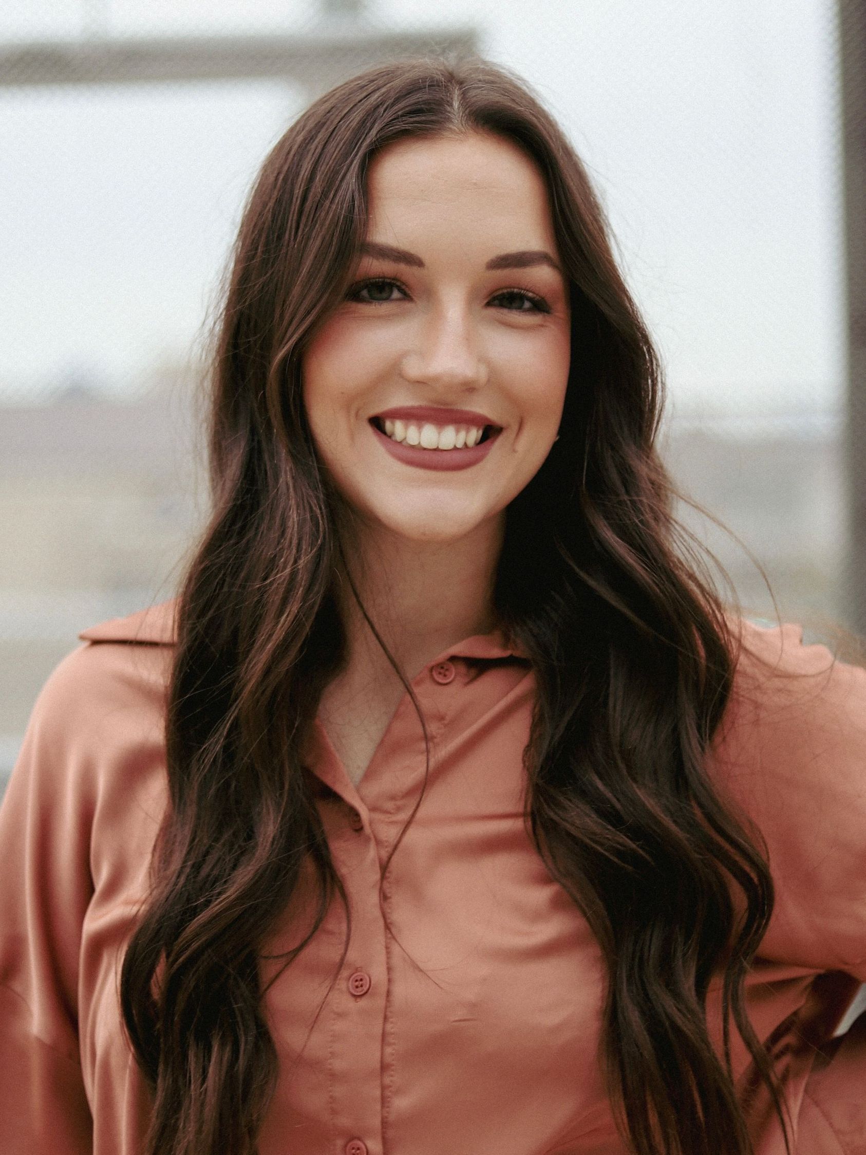 The woman is wearing a pink shirt and smiling for the camera.