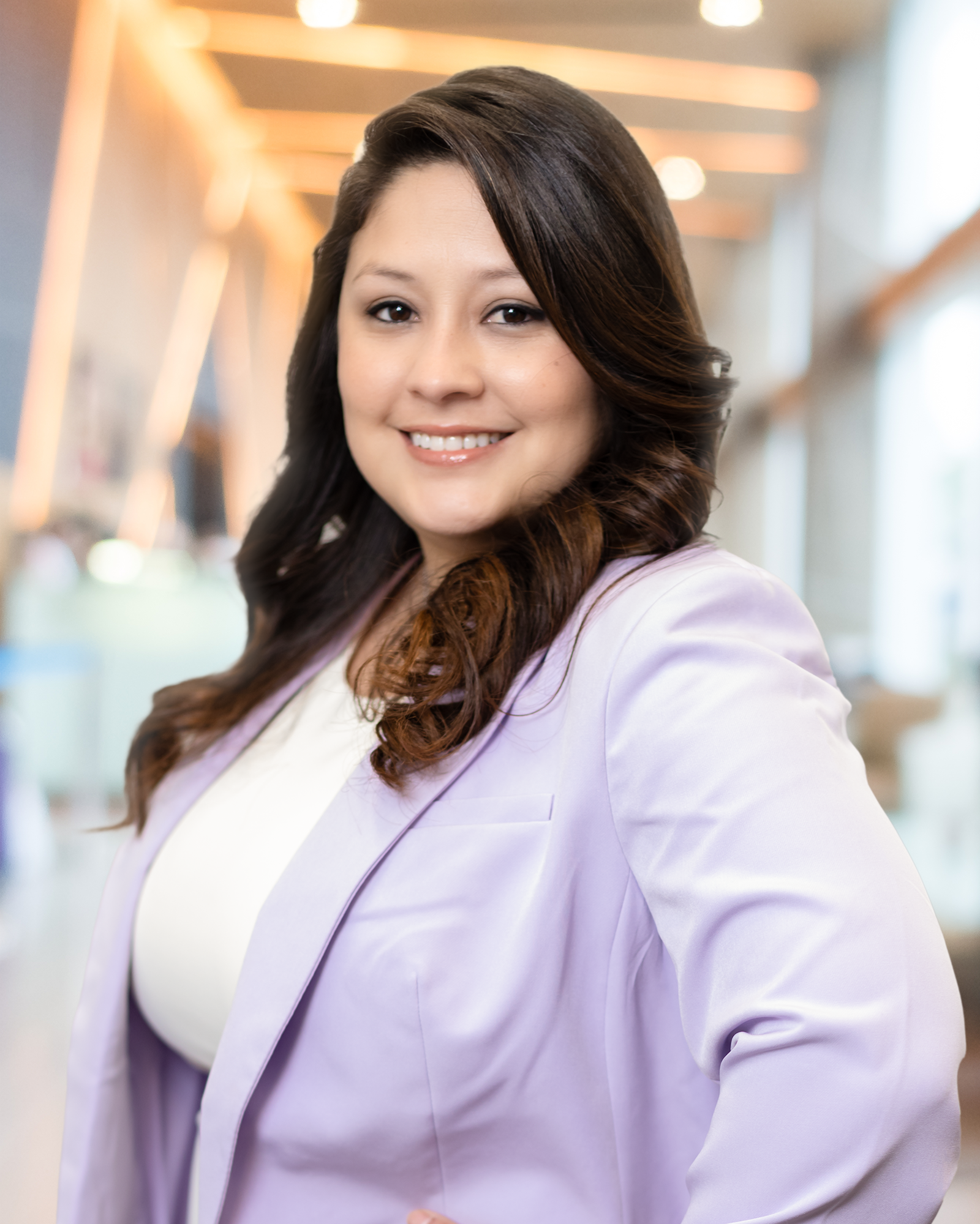 A woman in a purple jacket and white shirt is smiling for the camera.