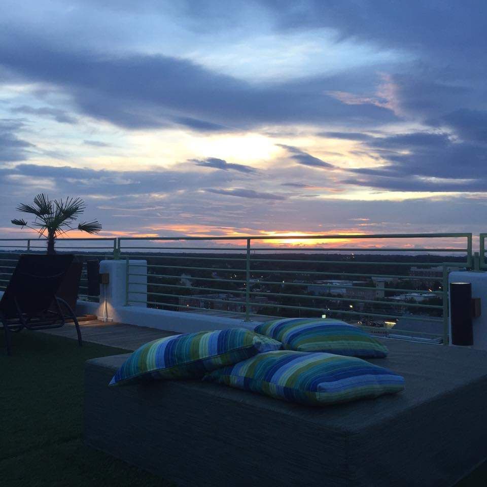 a balcony with a sunset in the background and pillows on the ground