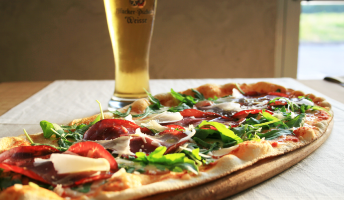 pizza ovale su un tagliere e un bicchiere di birra