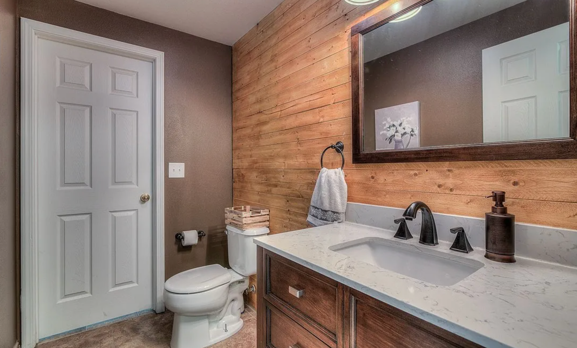 A bathroom with a toilet , sink and mirror.