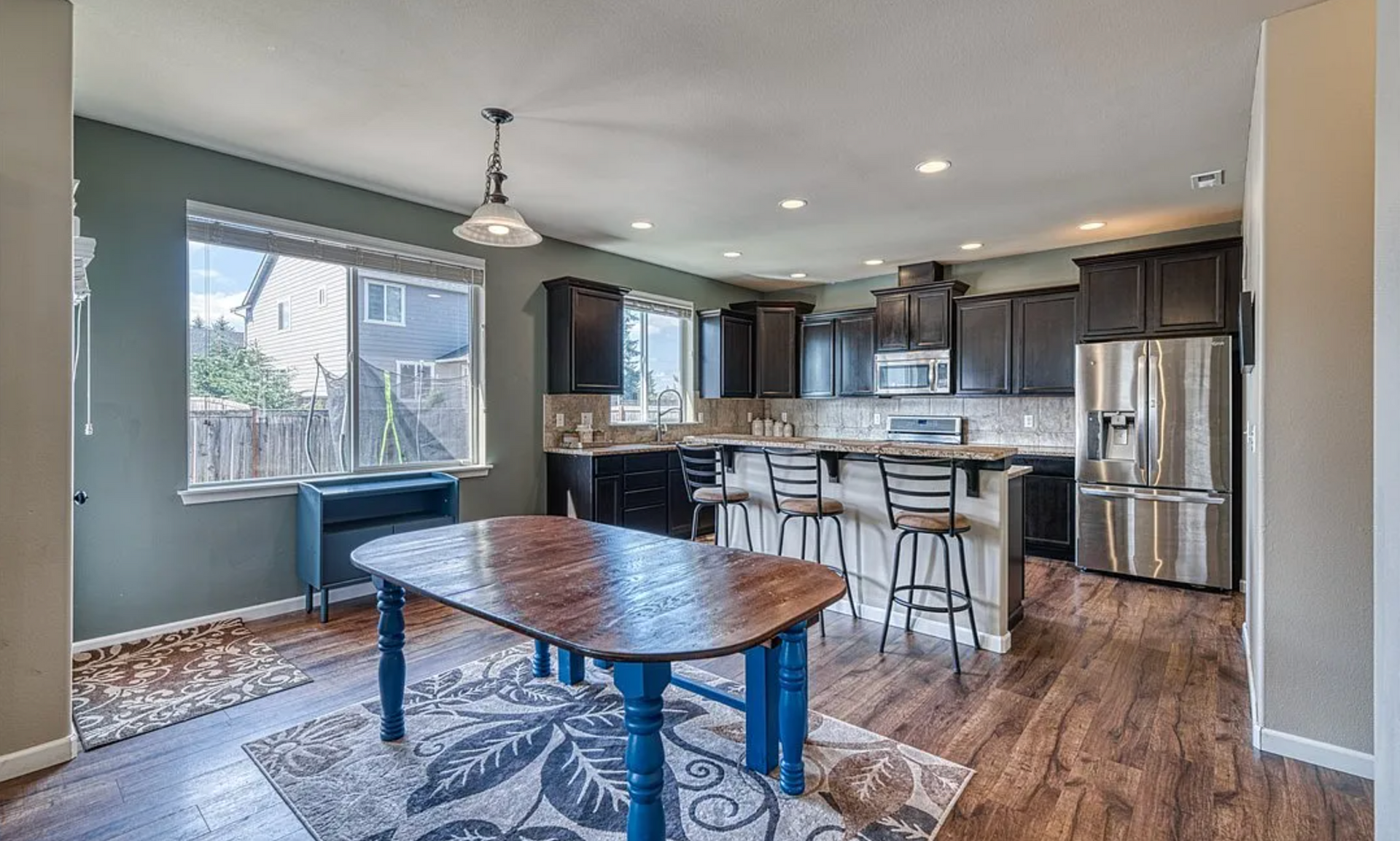 A kitchen with a table and stools in it.
