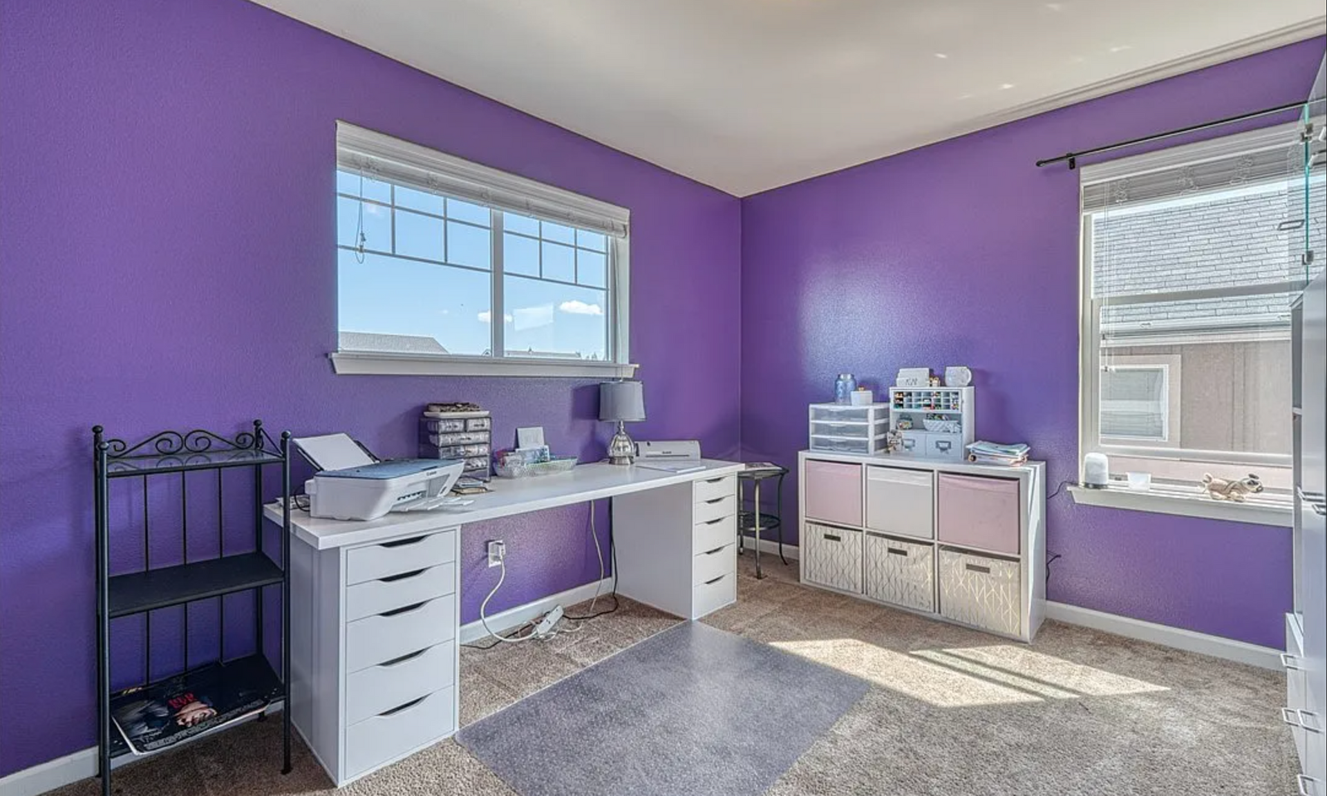 A room with purple walls and a white desk.
