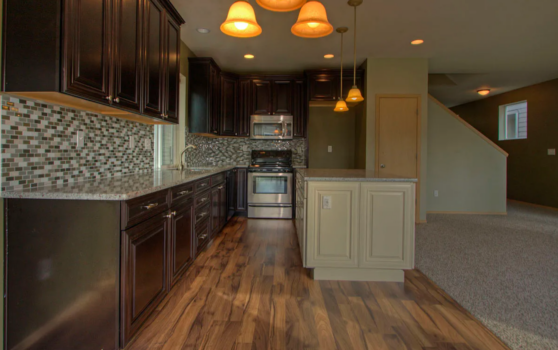 A kitchen with dark cabinets , stainless steel appliances , and a large island.