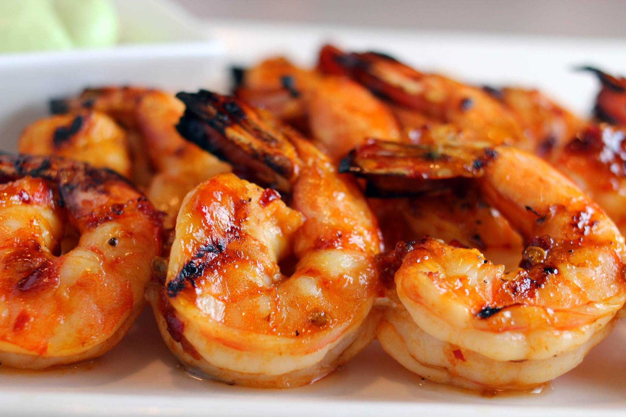 A white plate topped with grilled shrimp on a table.