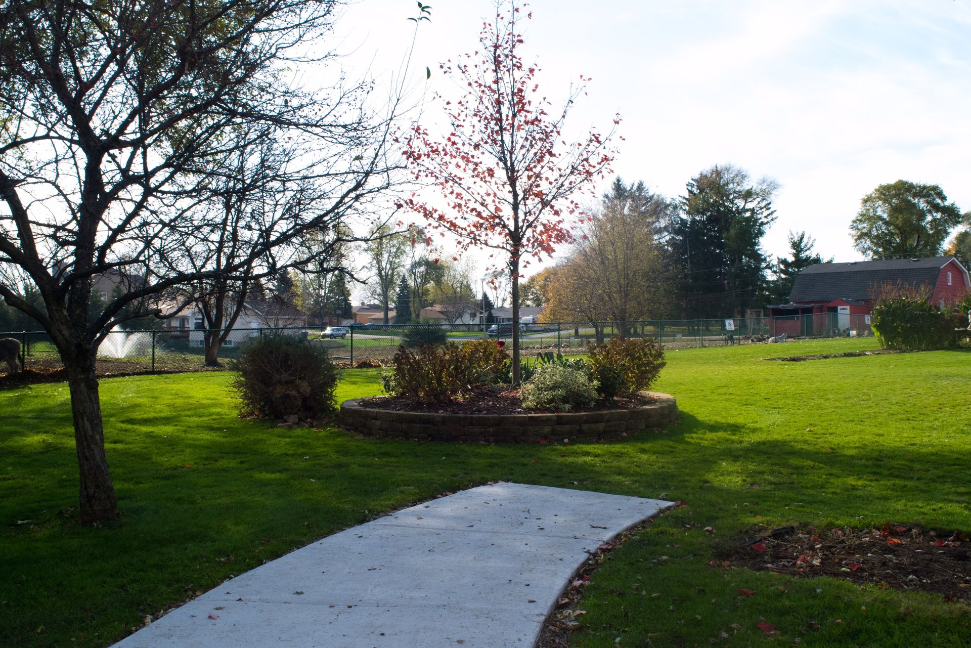 A path in a park with trees and a barn in the background