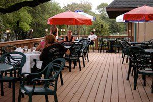 A group of people are sitting at tables on a deck with umbrellas