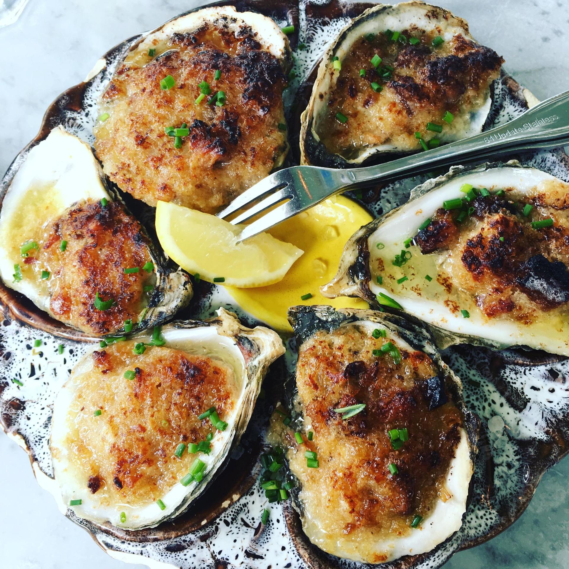 A plate of oysters with a fork and a slice of lemon