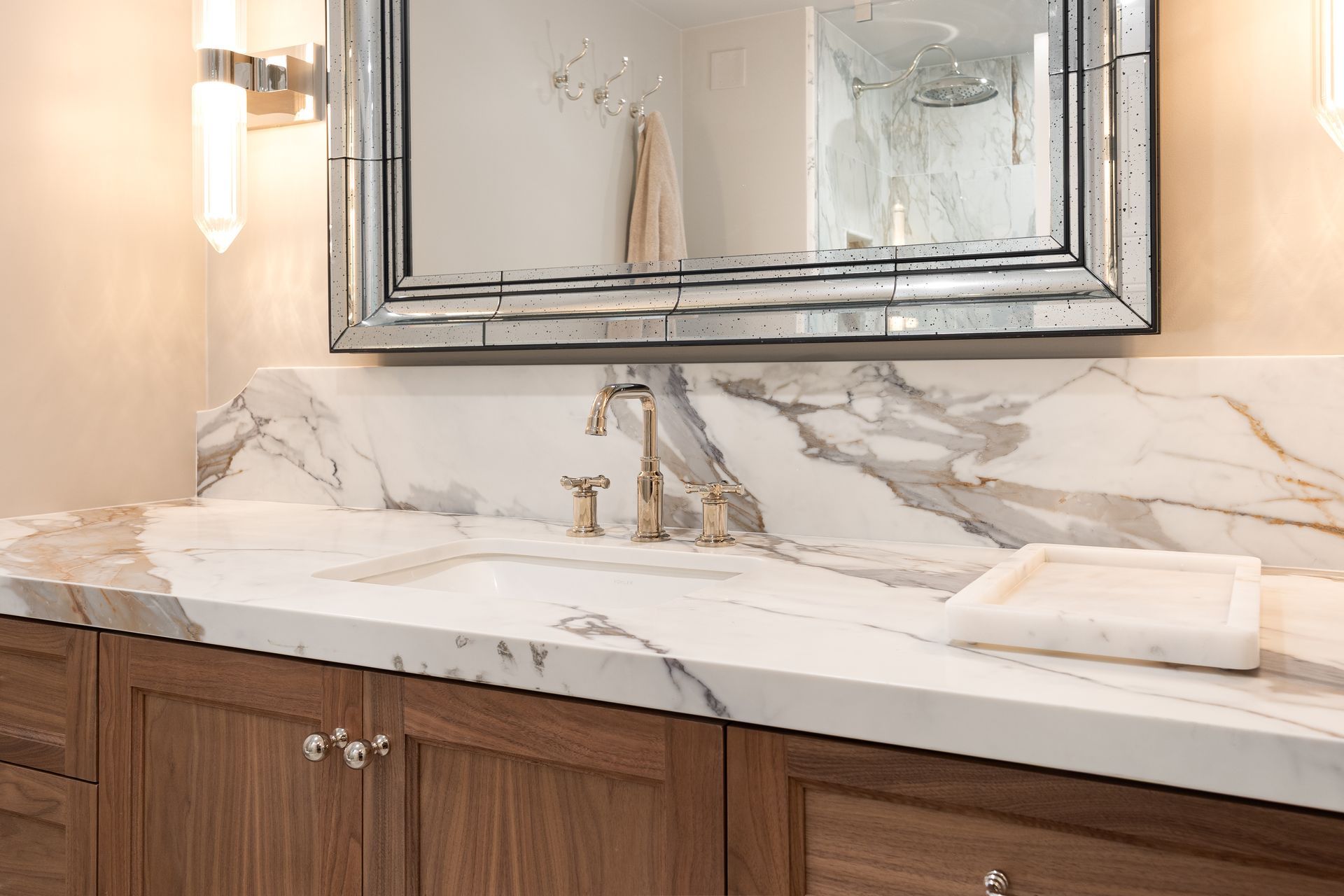 Bathroom vanity with marble countertop, wood cabinets, and large mirror.