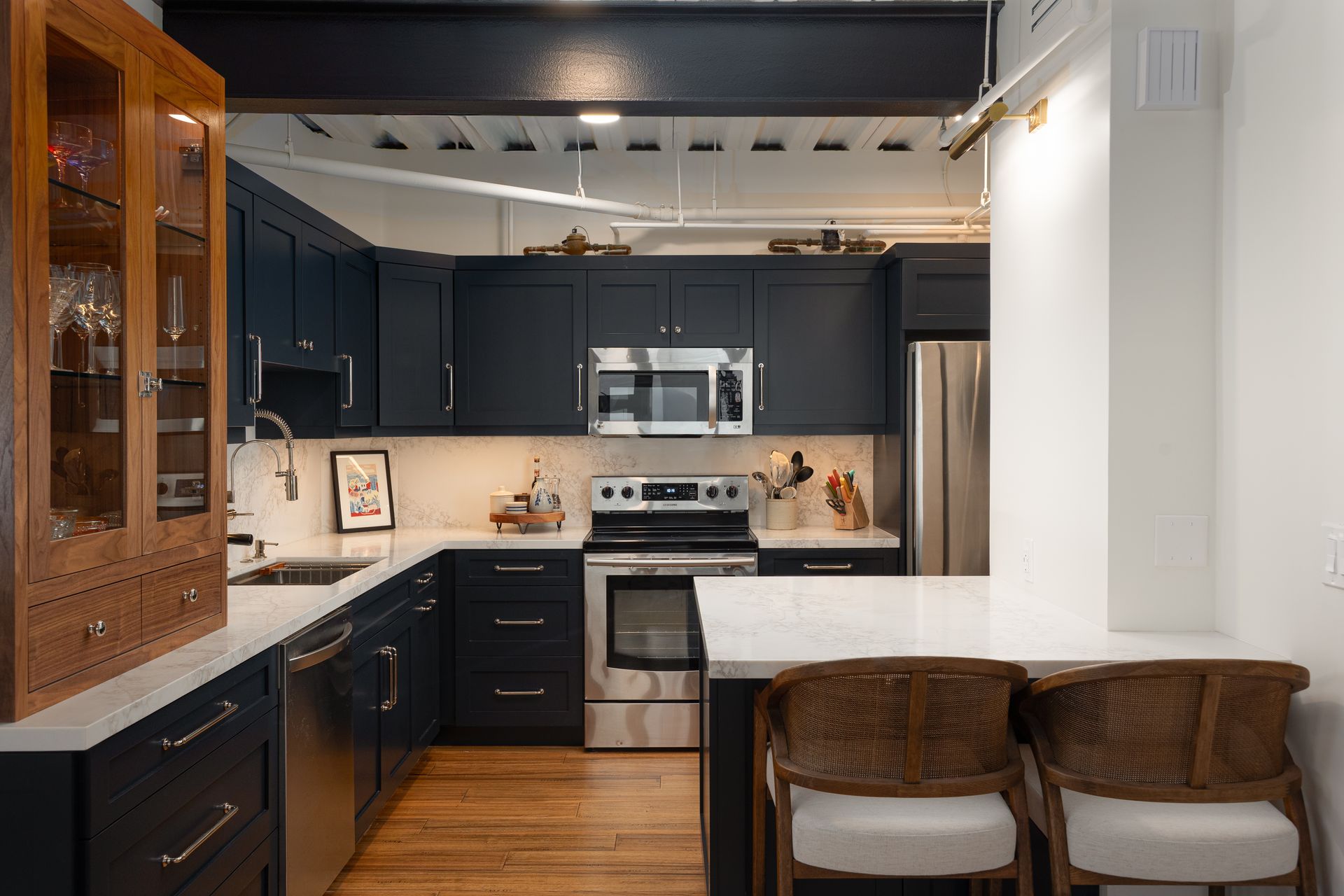 Modern kitchen with navy cabinets, stainless steel appliances, and wood floors.