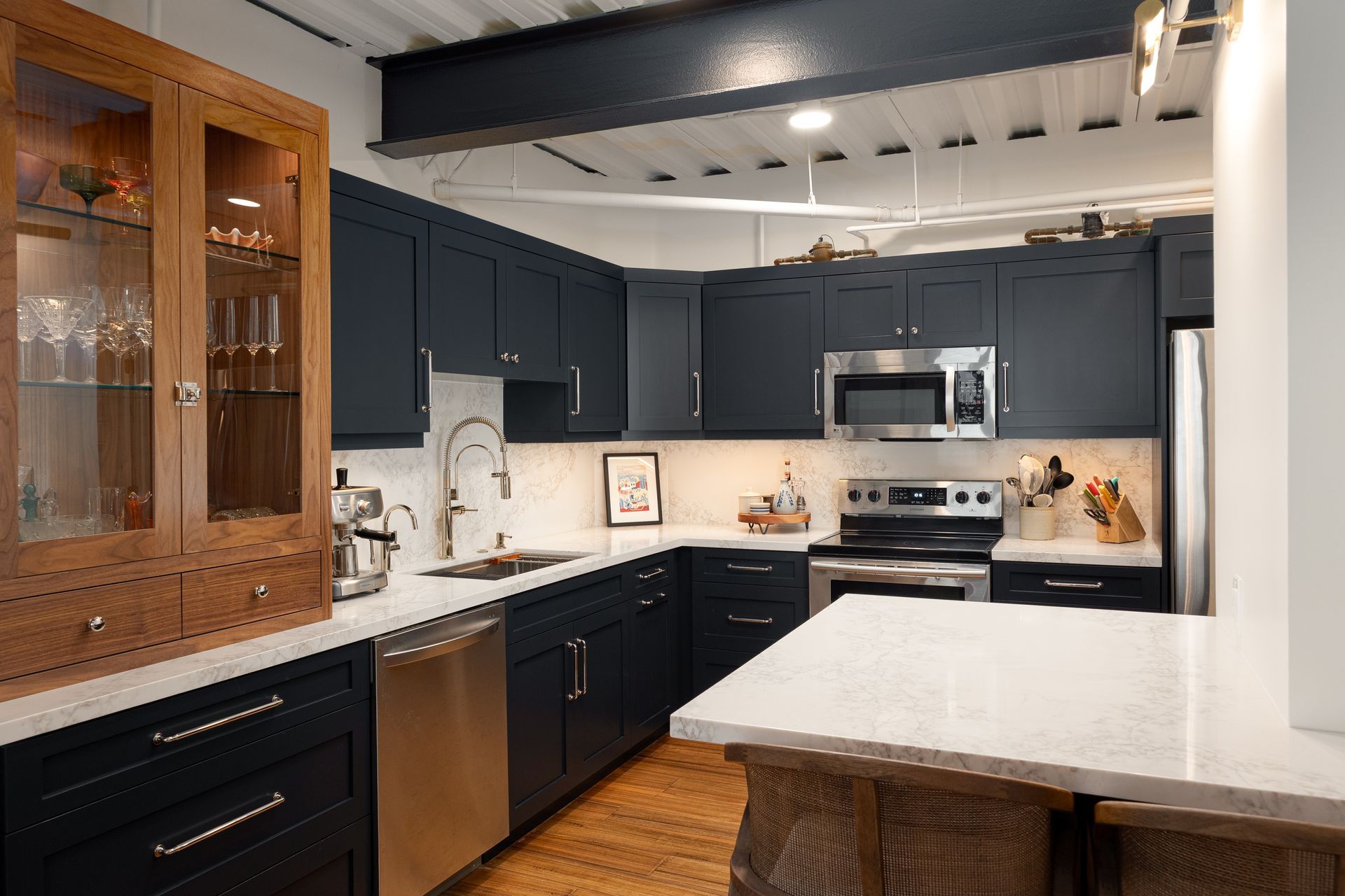 Navy blue kitchen with stainless steel appliances, white countertops, and wooden accents.
