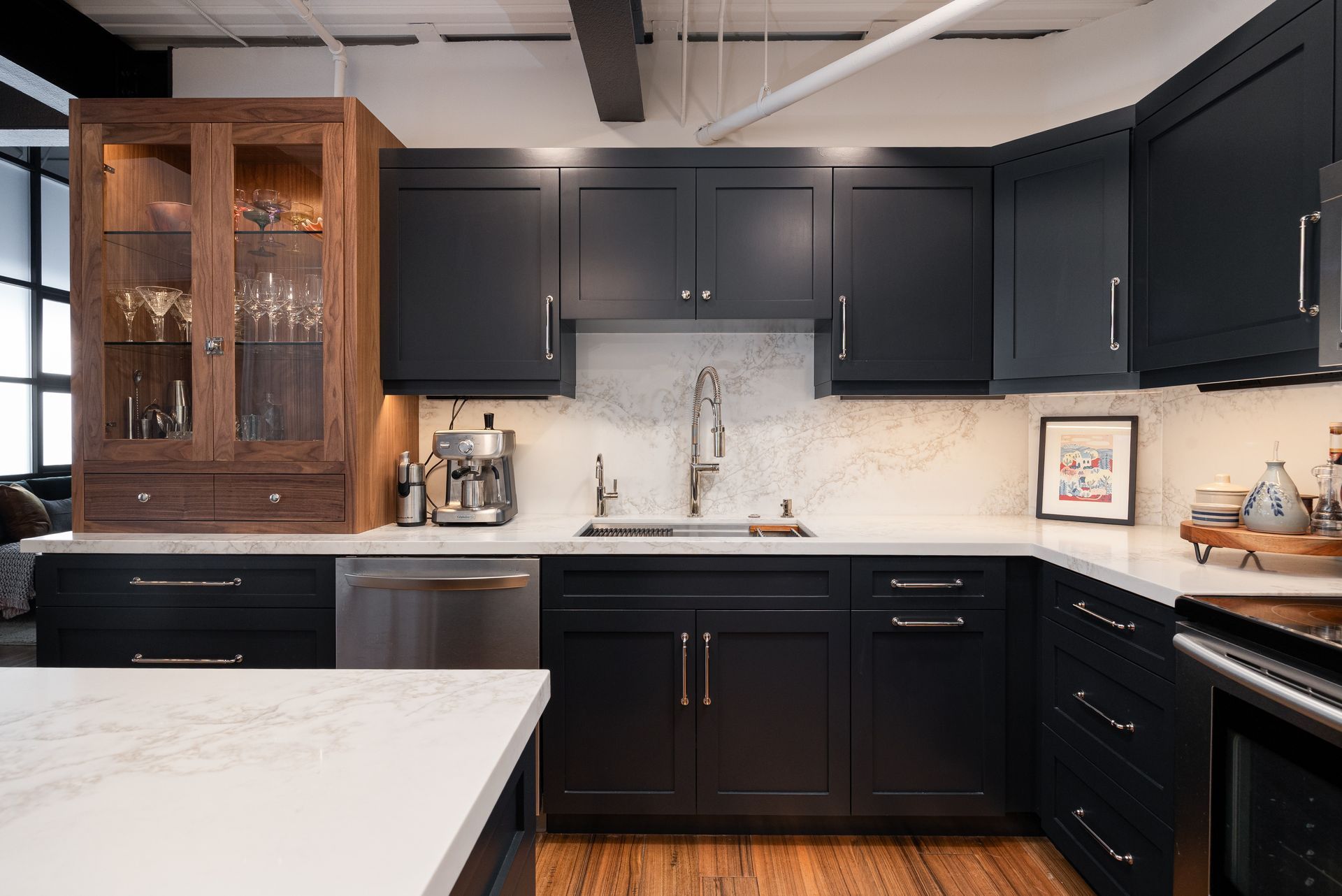 Dark blue kitchen cabinets with white countertops, stainless steel appliances, and wooden flooring.