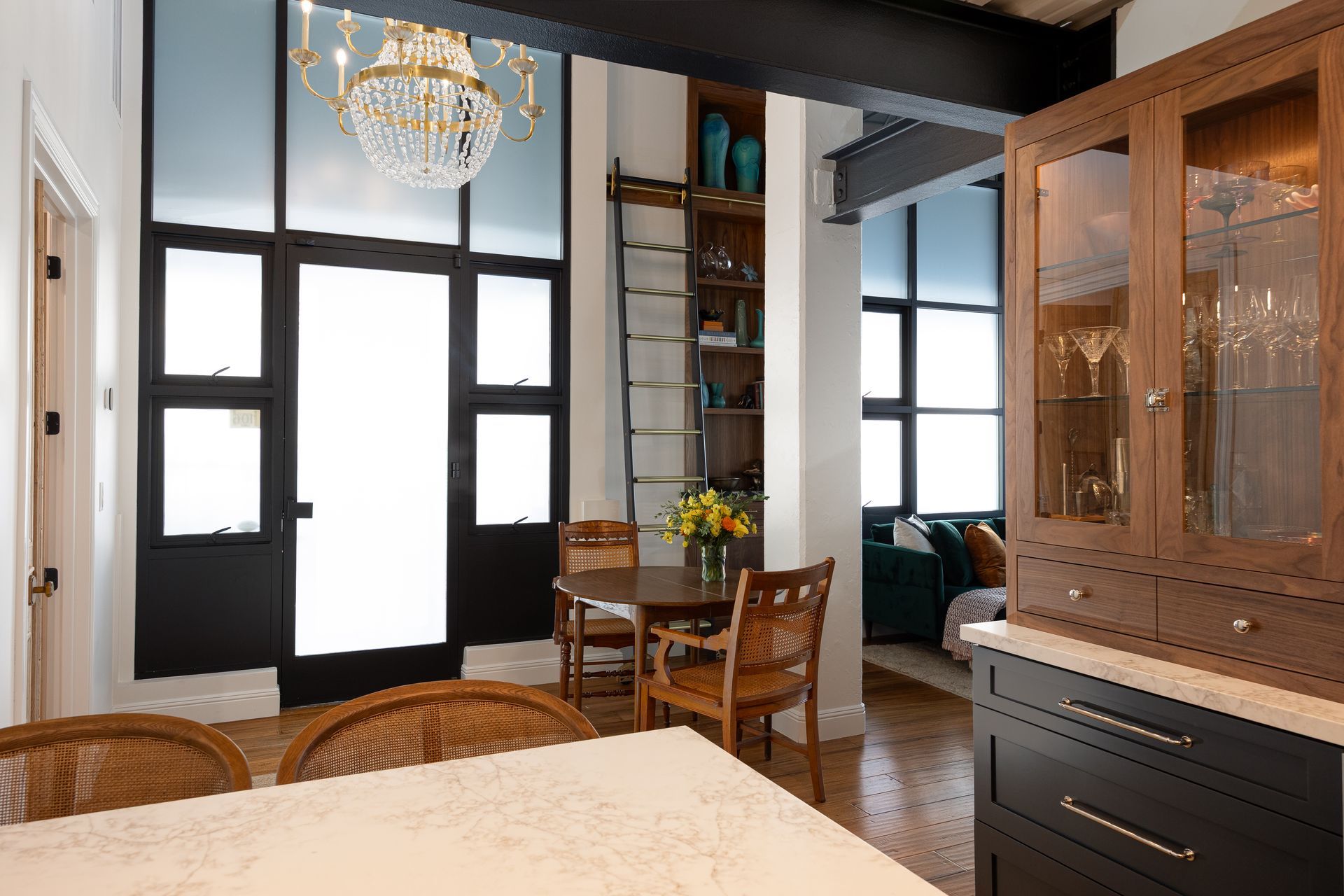 Kitchen with dark cabinets, a wooden table, and a black door with frosted glass.