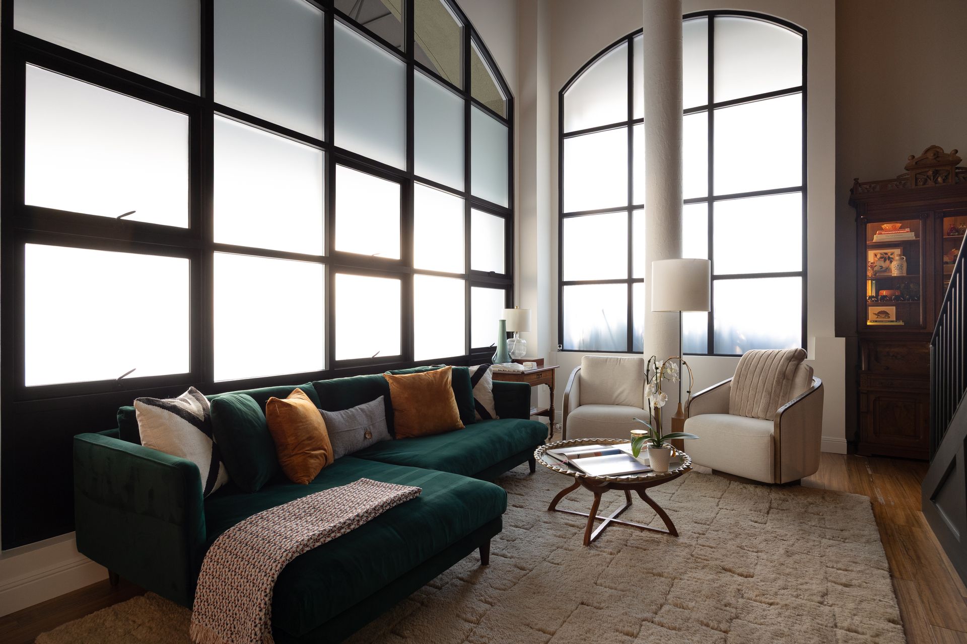 Living room with a green sectional, two armchairs, and large frosted windows.