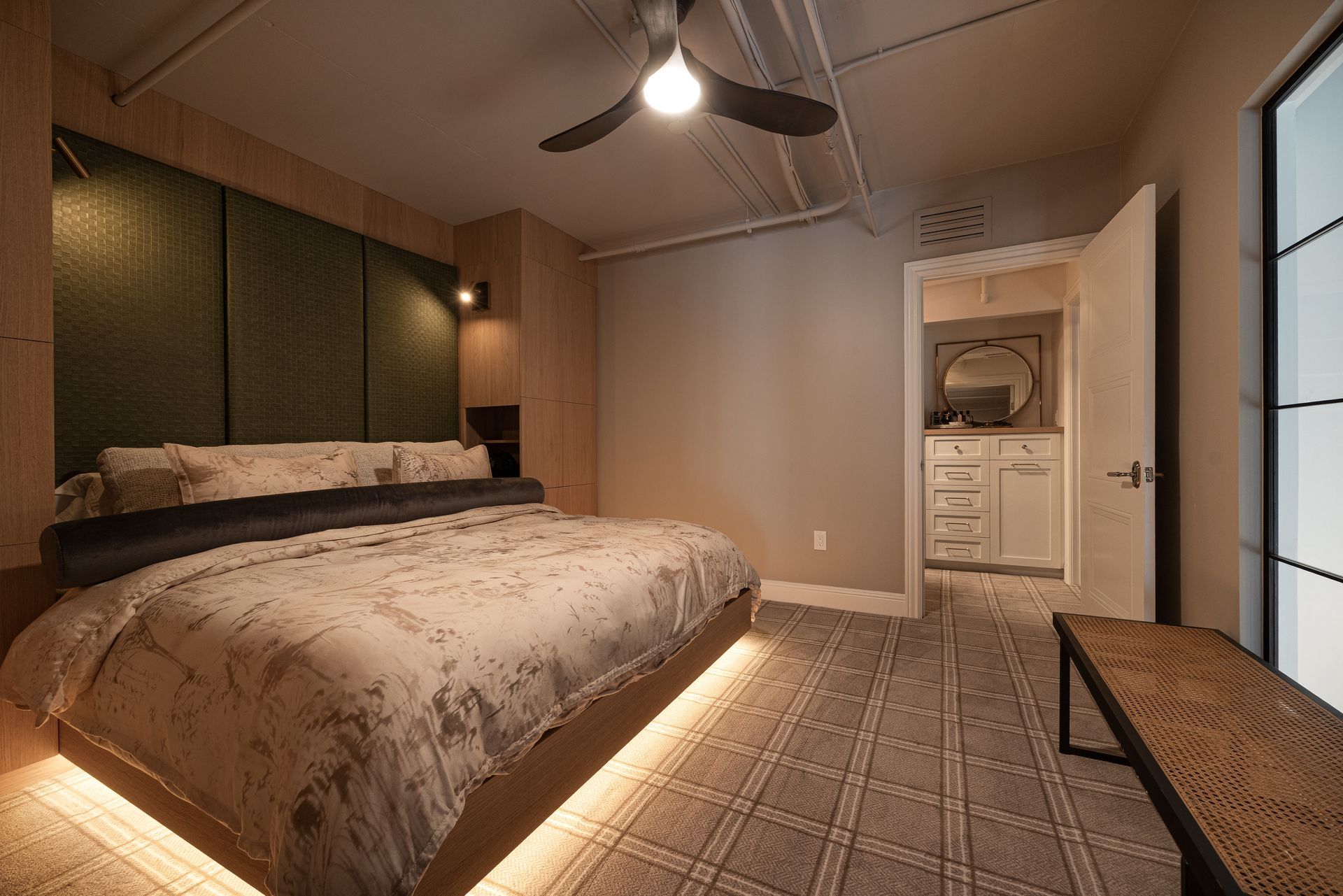 Bedroom with a large bed, lit from underneath, with an ensuite bathroom visible.