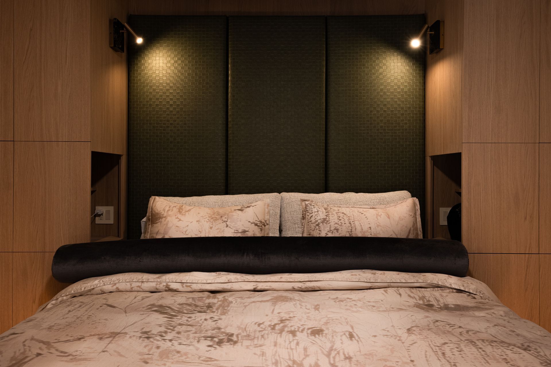 Bedroom with a bed. Green padded headboard, tan wood paneling. Overhead lighting.