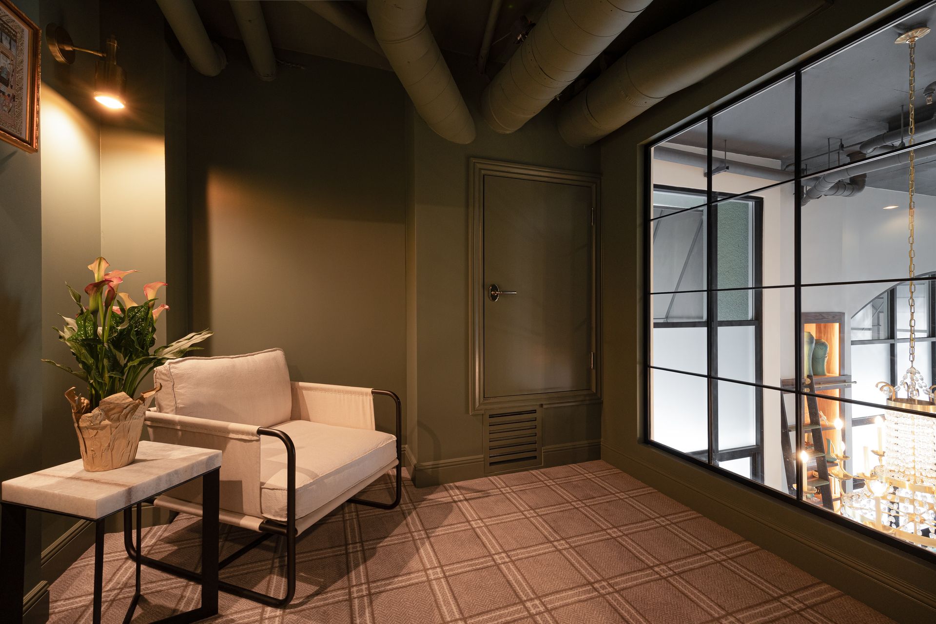 Cozy waiting area with a white armchair, small table with flowers, and a large window.