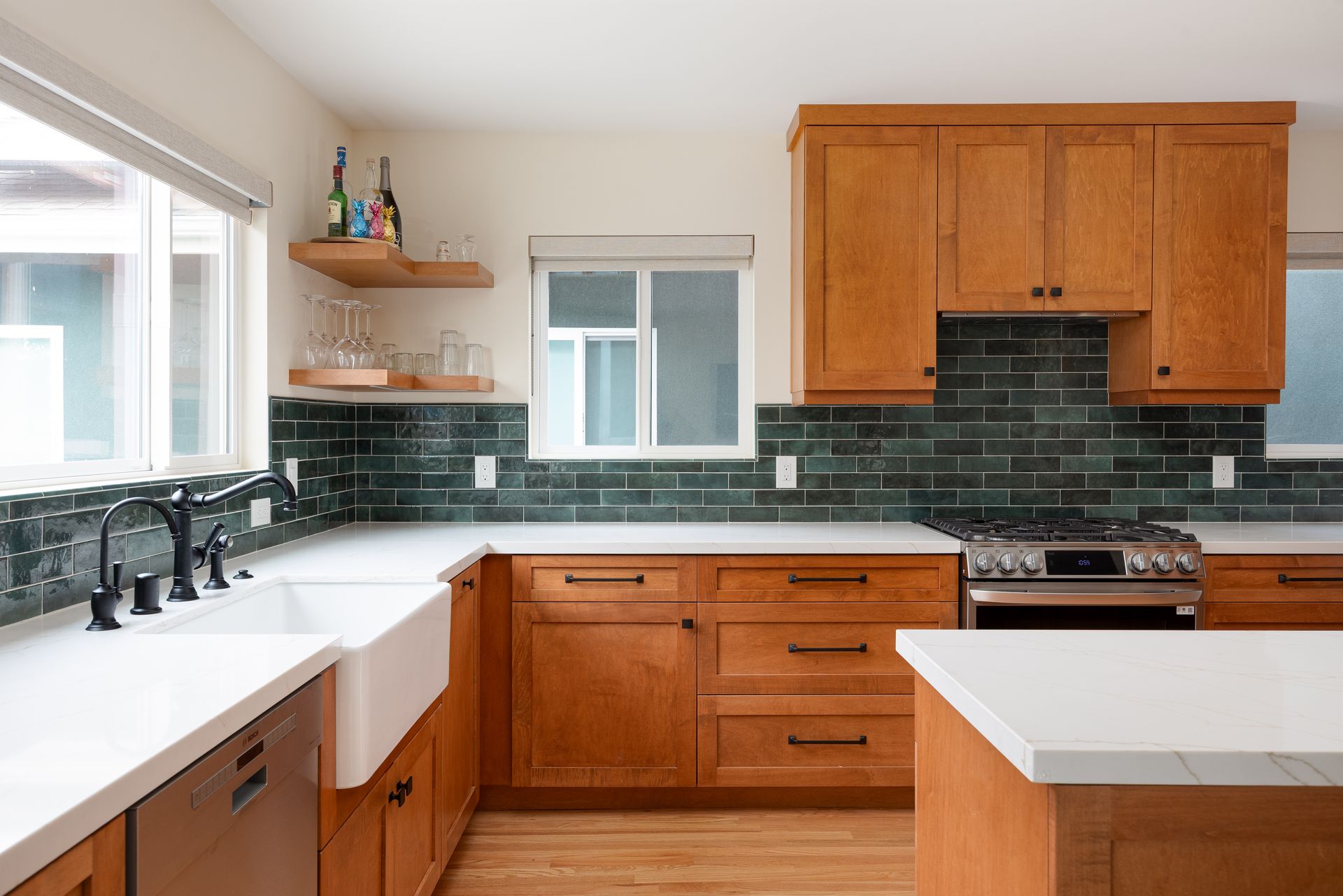 Kitchen with wood cabinets, white countertops, and dark green tile backsplash.