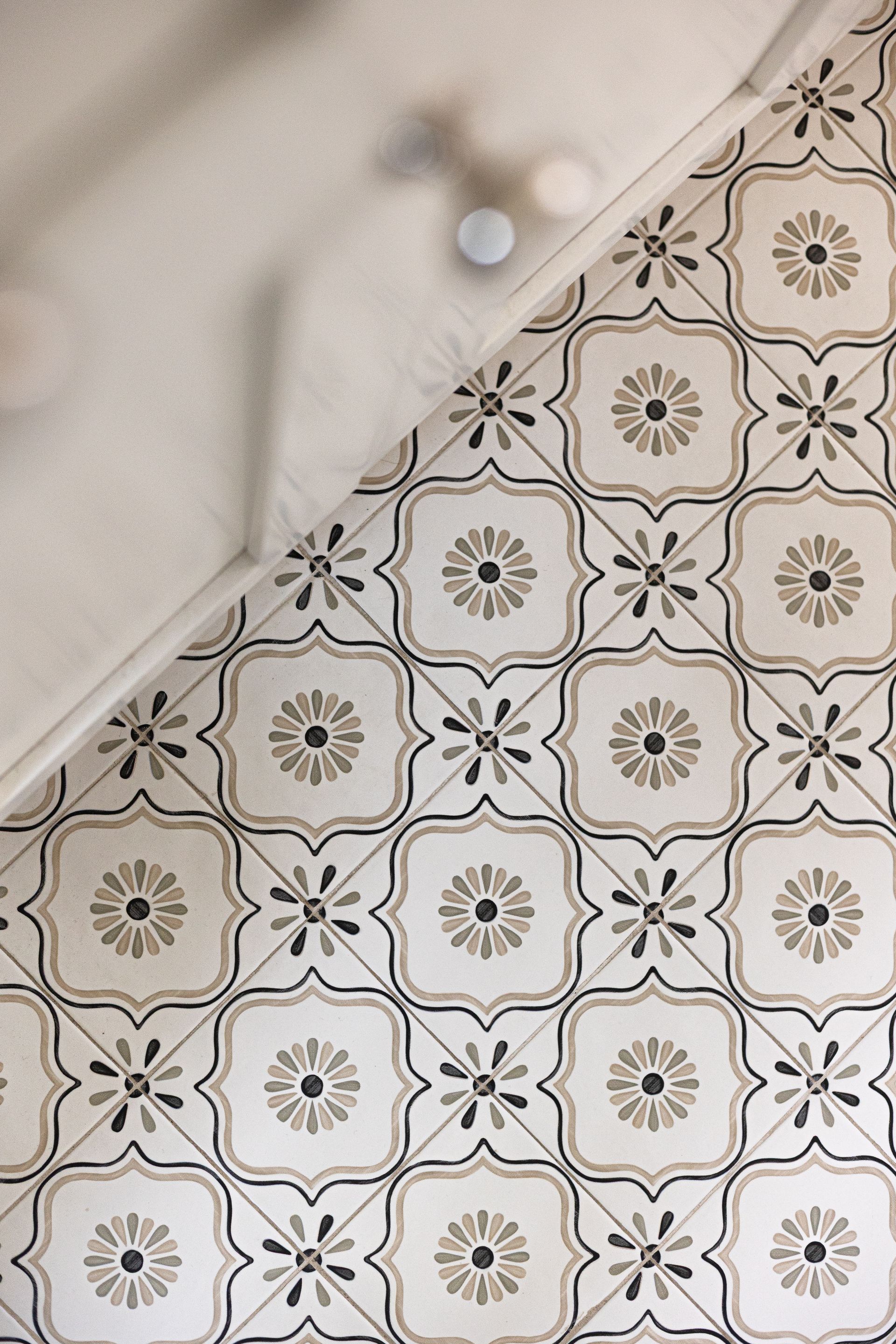 Floral tile floor with a white cloth partially covering it.