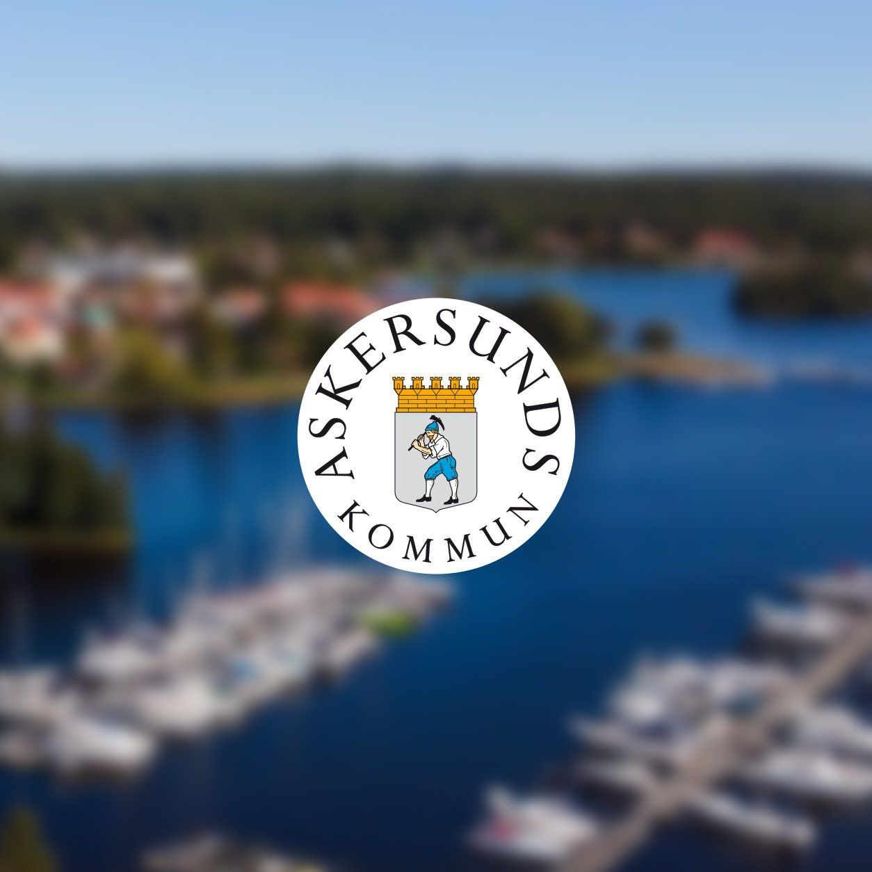 Askersunds kommuns logotyp mot en flygbild över staden