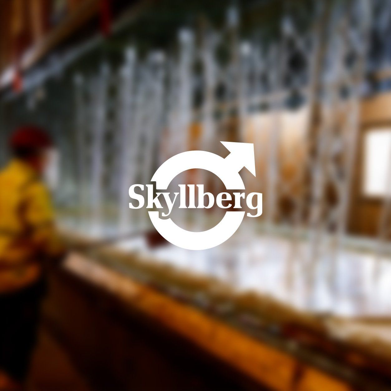 Skyllbergs Bruk-koncernens logotyp mot en bild från Defabs förzinkningsfabrik