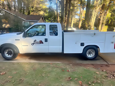 A white utility truck is parked in a driveway in front of a house.