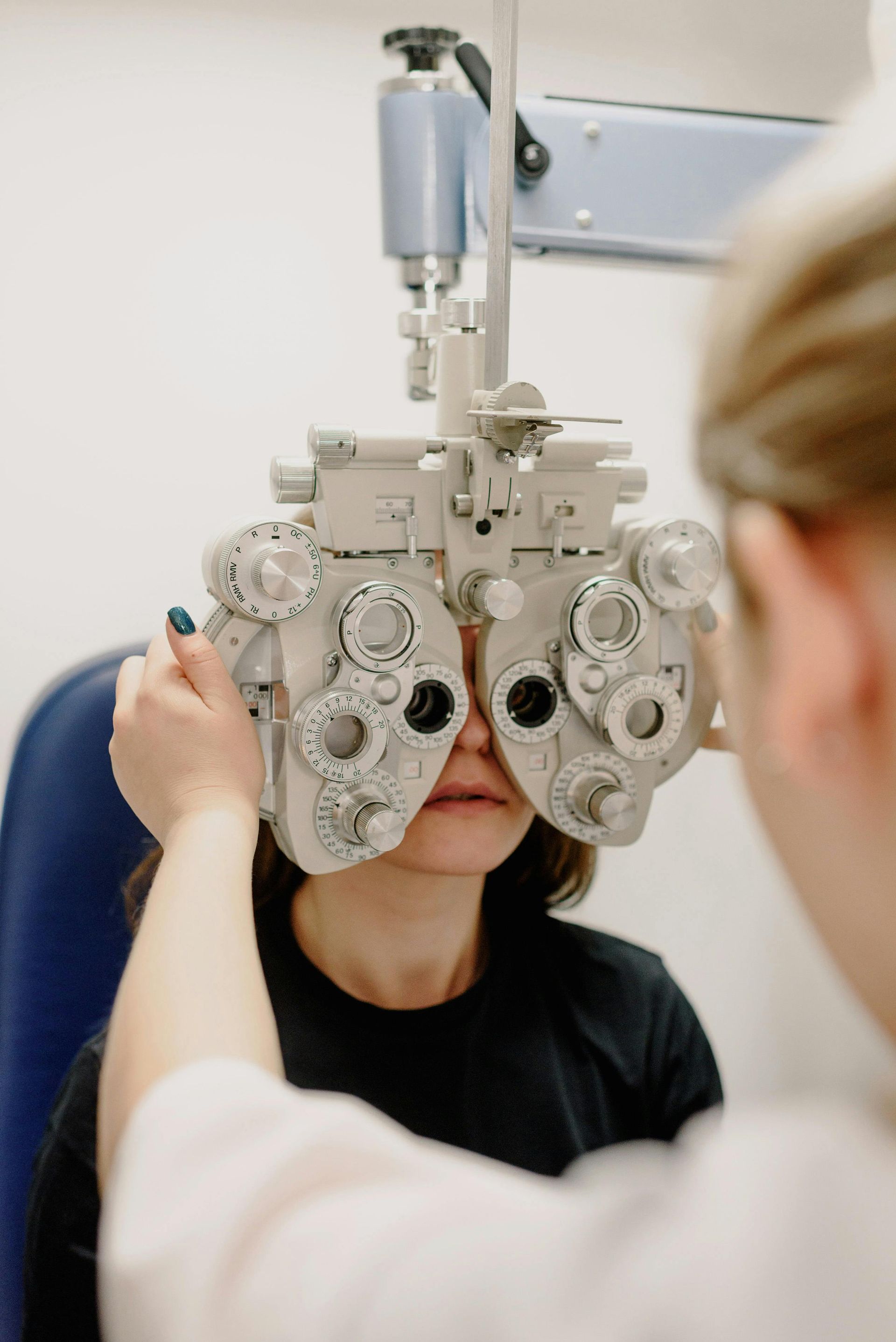 Optometrist using phoropter to examine a patient's eyes in a medical office.