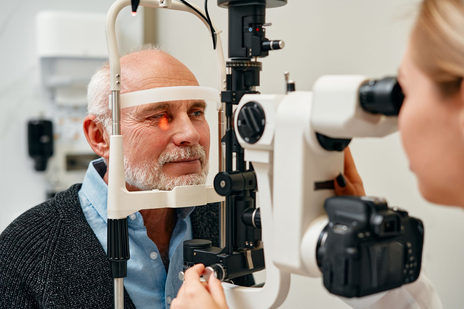 Elderly man getting an eye exam with a slit lamp by a doctor.