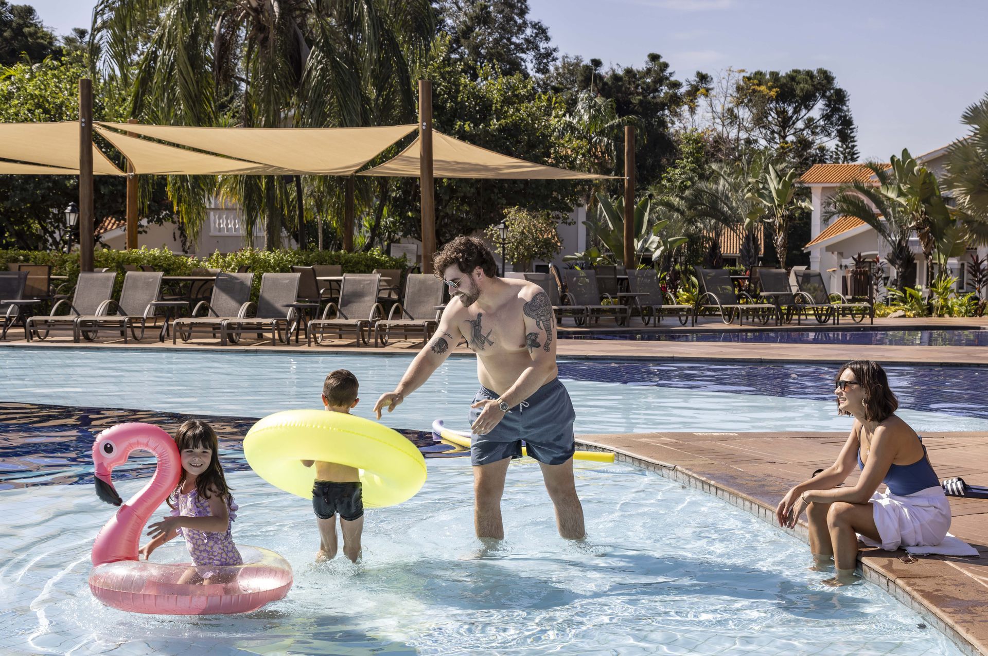Uma família está brincando em uma piscina com uma bóia de flamingo.