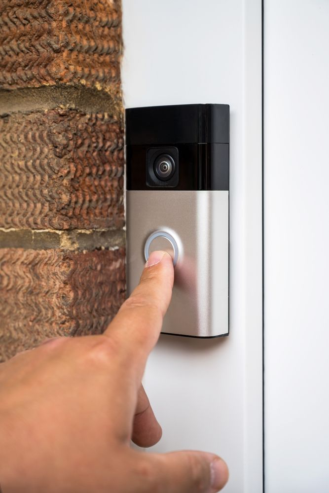 Een persoon drukt op een knop op een deurbel.