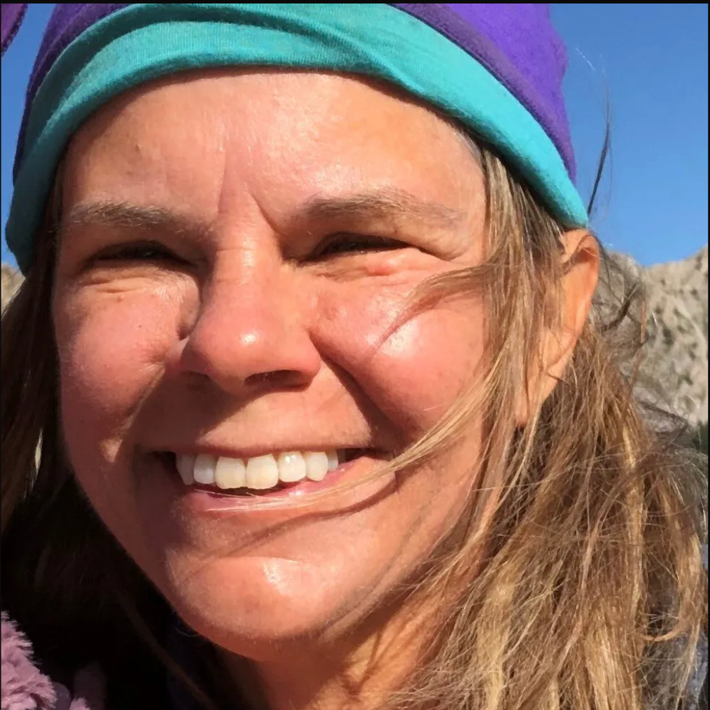 A woman wearing a purple and blue headband smiles for the camera