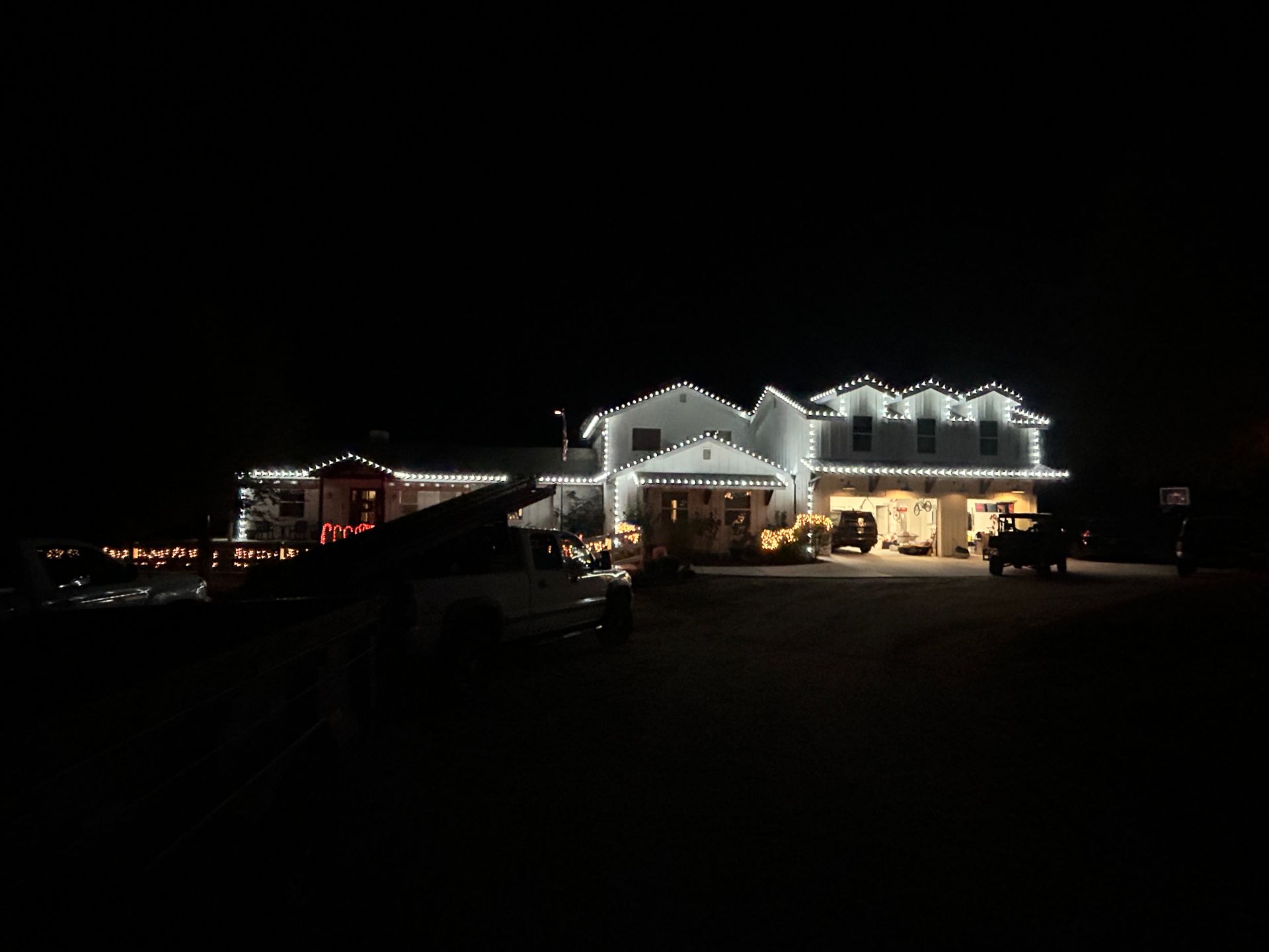 A large white house is lit up at night with christmas lights.