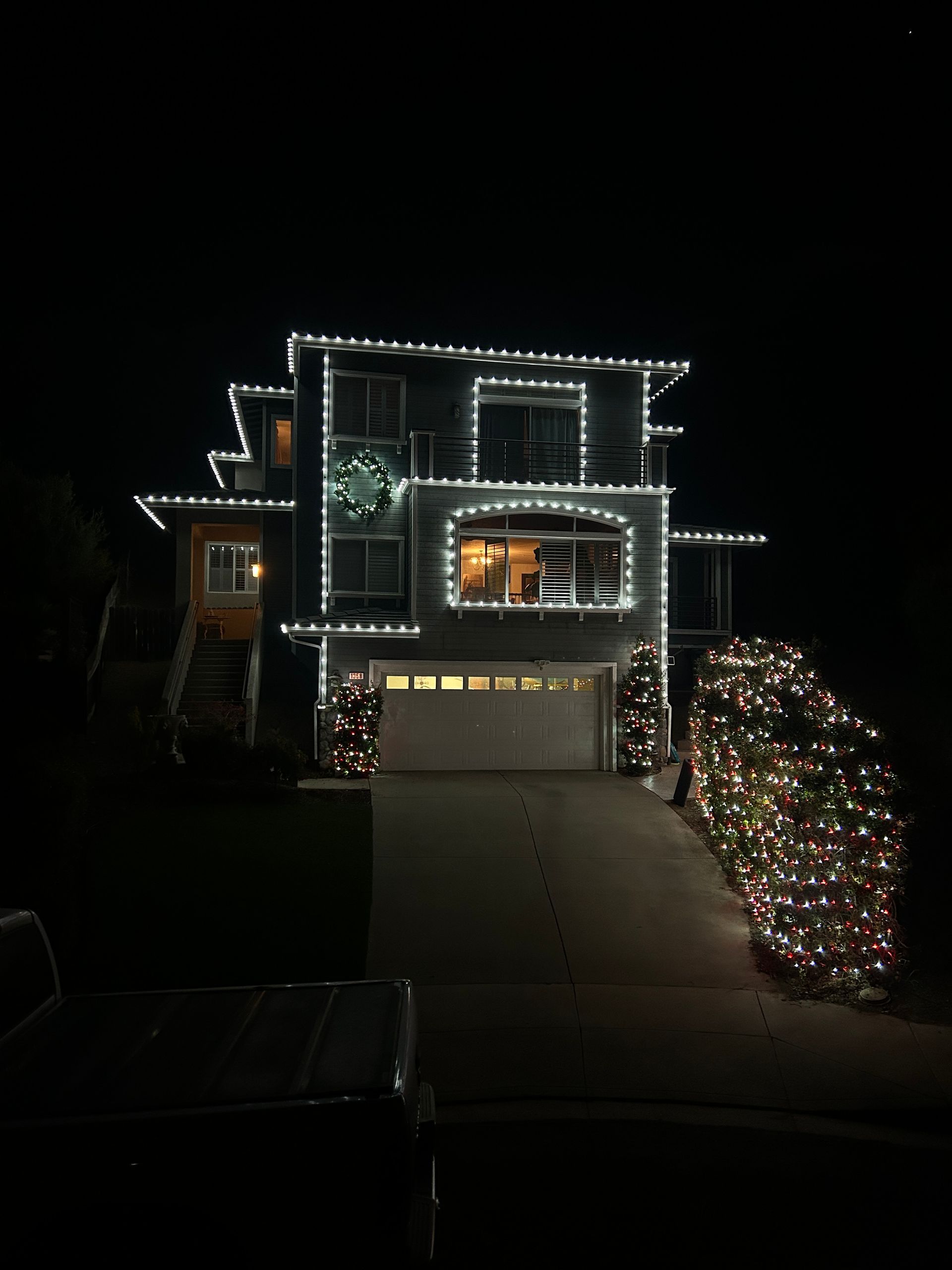 A large house is decorated with christmas lights at night.