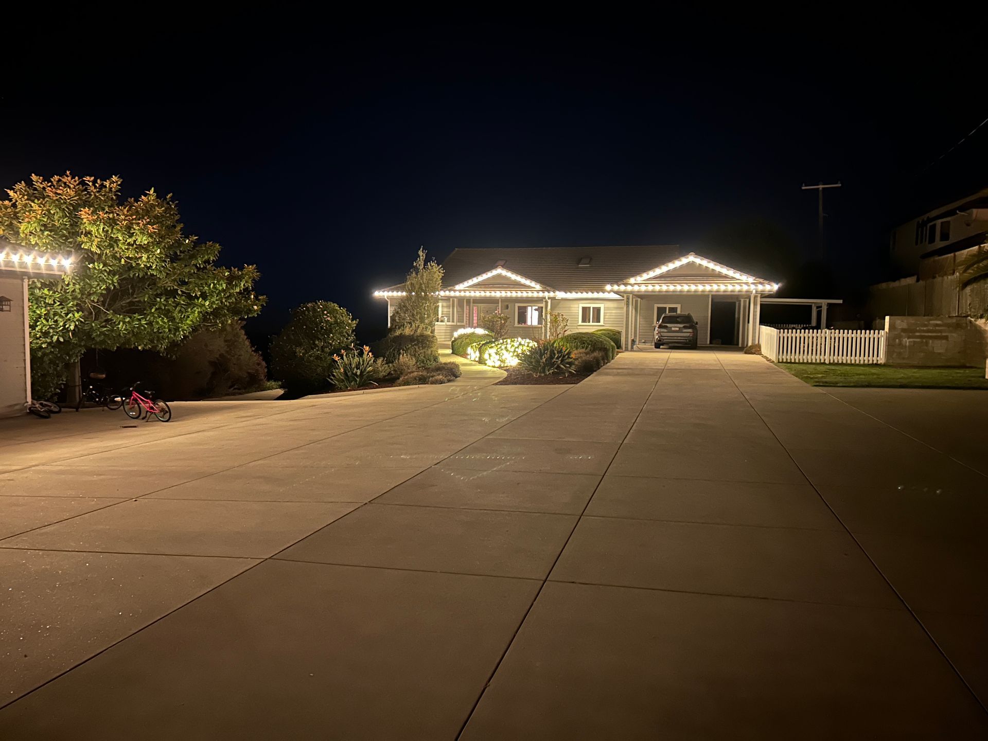 A house with christmas lights on it is lit up at night.