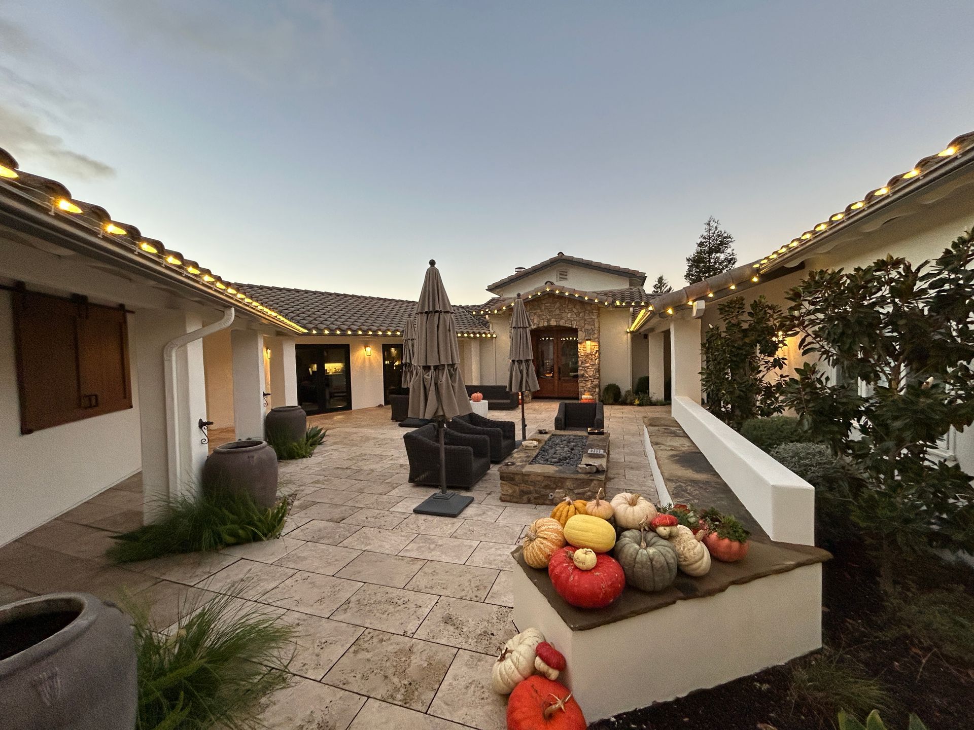 A patio with pumpkins and umbrellas in front of a house.